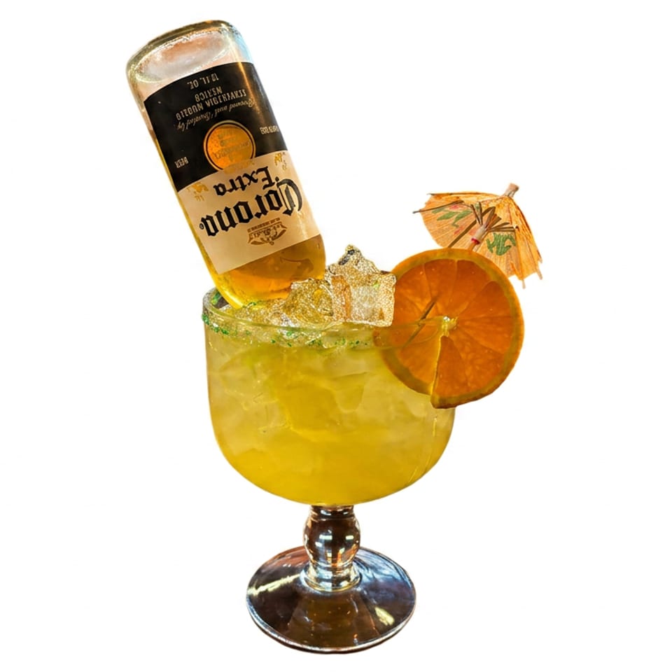Corona Extra bottle inverted into a large, iced margarita with a green rim, orange slice, and umbrella.